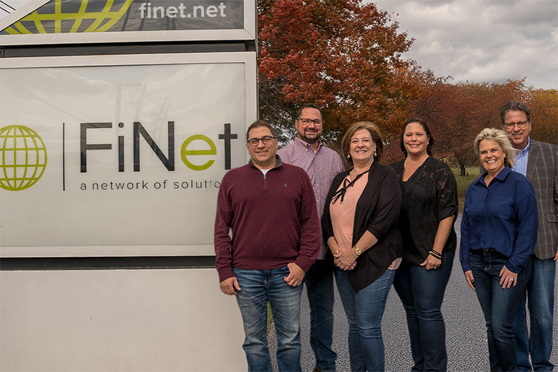 The FiNet leadership team posing next to the FiNet sign.